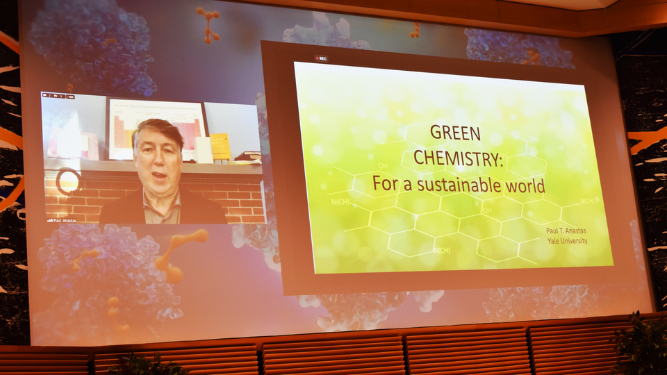 To the left, a man talking on a screen. To the let, a screen showing the words Green chemistry for a sustainable world.