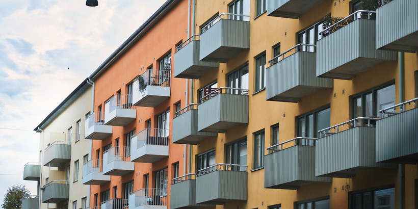 Lägenhetshus i olika färger med gråa balkonger.