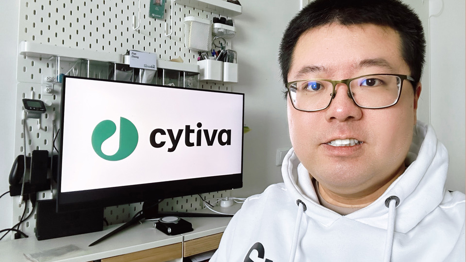 To the left a computer screen with the logo Cytiva, to the right a young man in glasses.