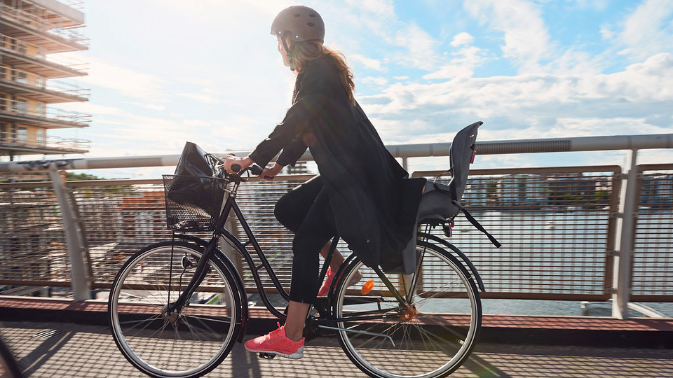 En kvinna cyklar över en bro i en stad-